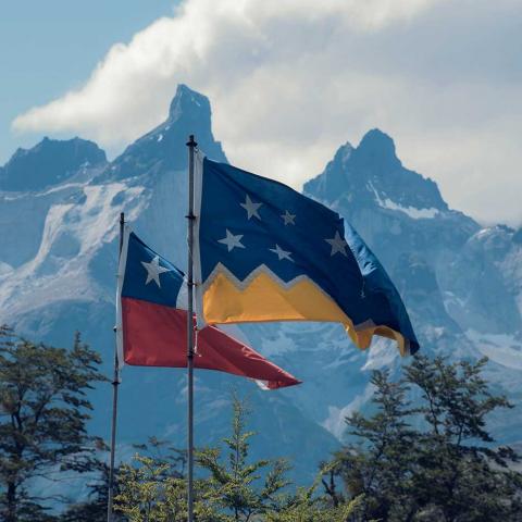 Flaggor som vajar framför ett berg i solsken i Chile