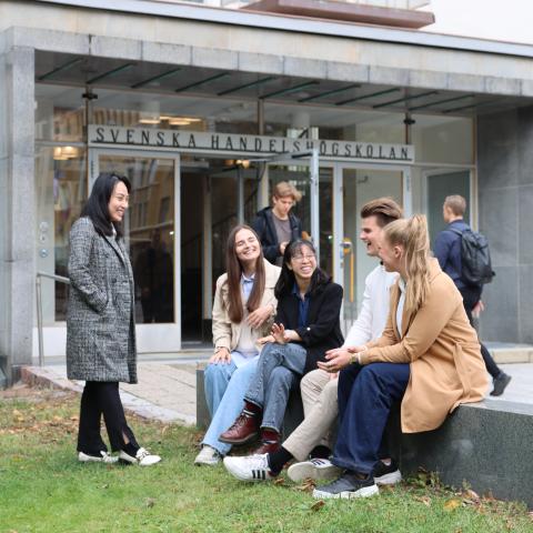 En grupp studenter sitter utanför Hanken i Helsingfors