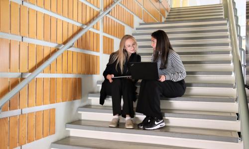 Två studerande sitter på trappan
