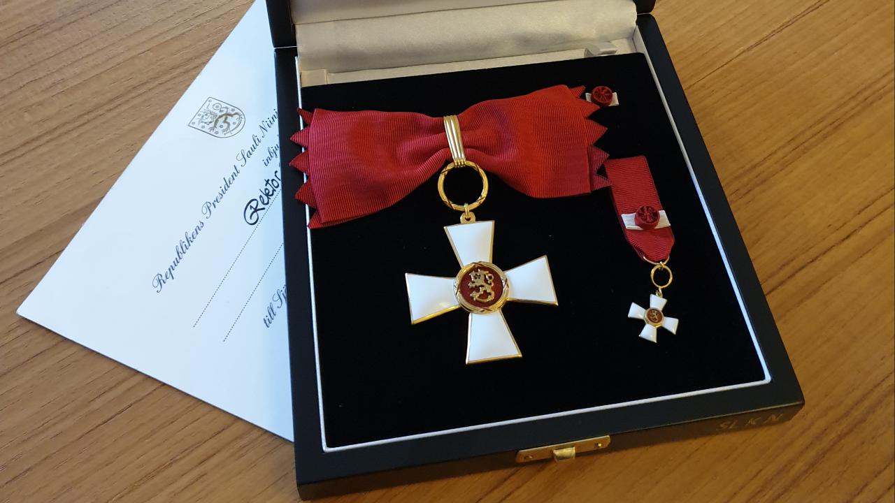 En bild på Karen Spens utmärkelsetecken Kommendörstecknet av Finlands Lejons orden i sin ask.
