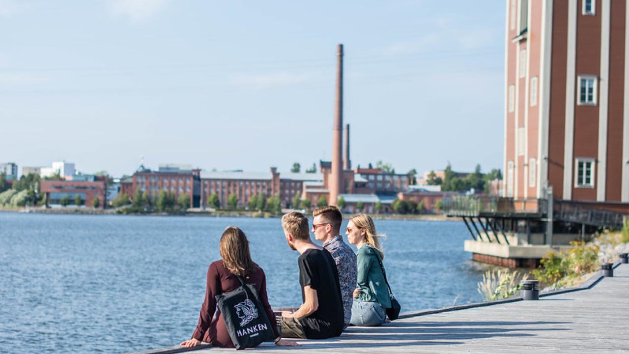 4 personer sitter på brygga vid strandkanten 