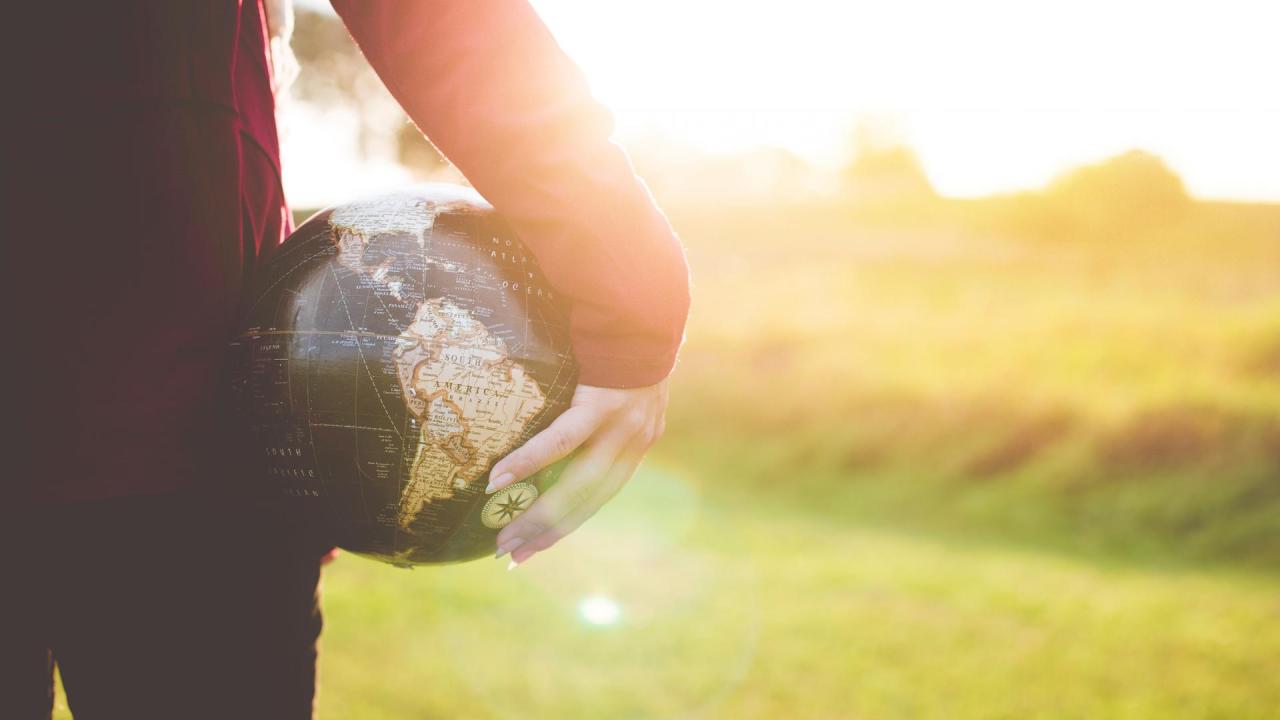 A man holding a globe at his hip.