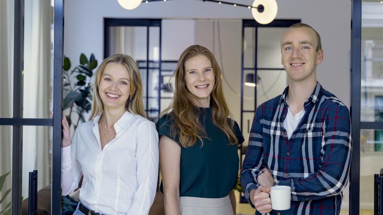 Två unga kvinnor och en ung man som småler