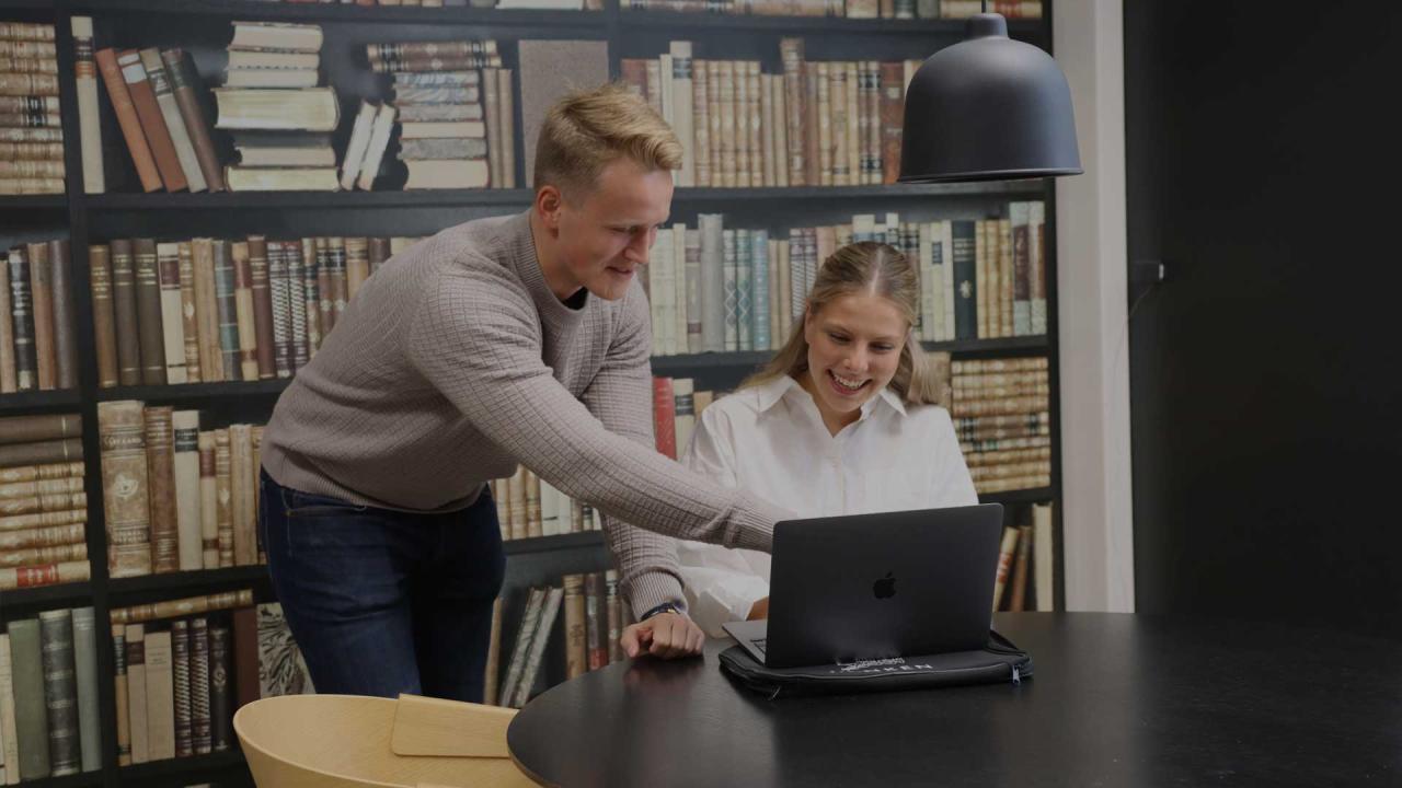 Två glada personer framför en laptop