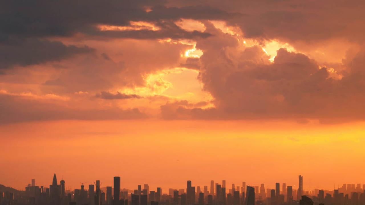 Stadslandskap i horisonten med solljus bakom molnen