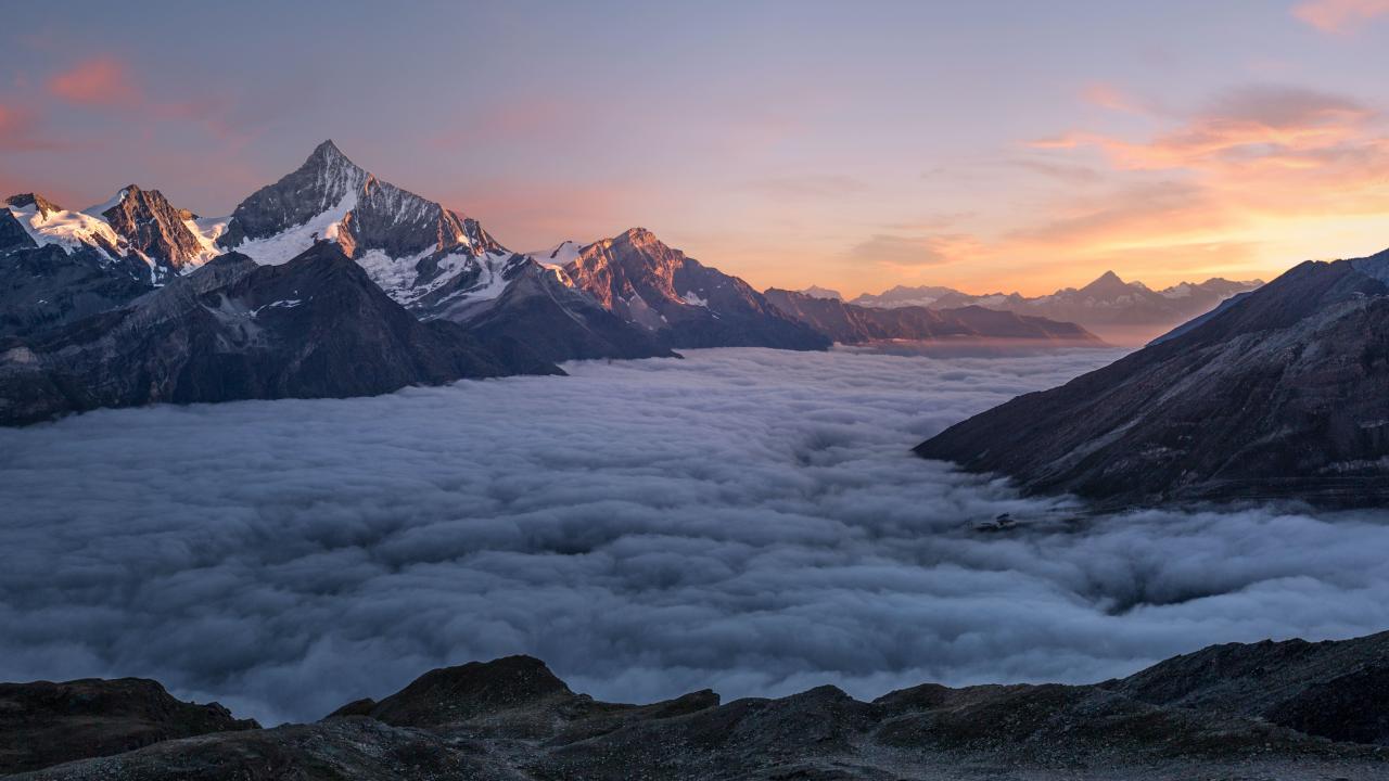 Höga bergstoppar ovanom molnen