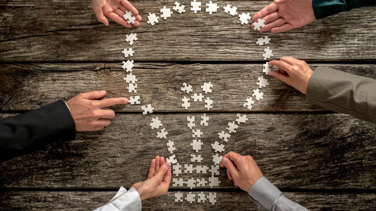 Händer som lägger ett pussel i form av en glödlampa