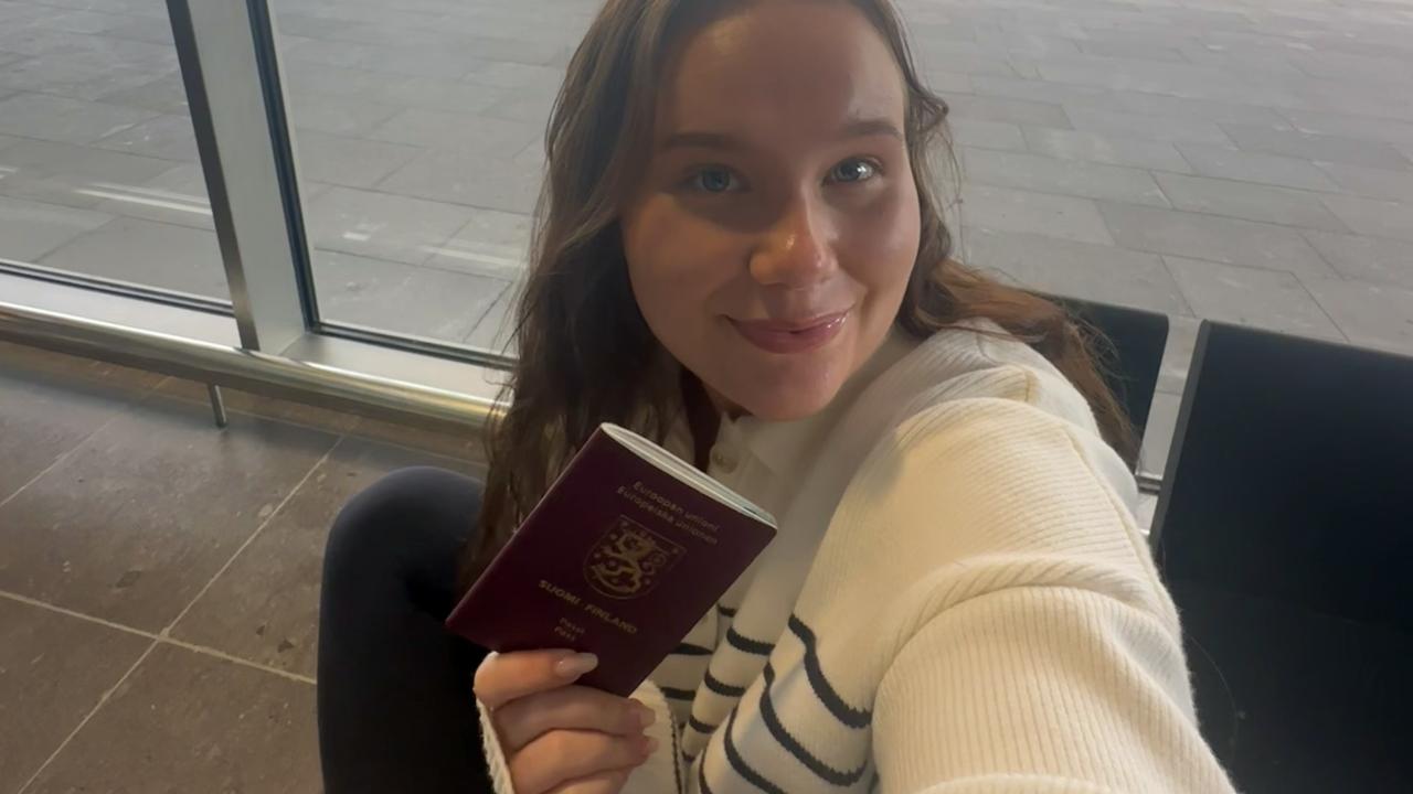 Hanna Udd sitter på ett flygfält med sitt pass i handen.