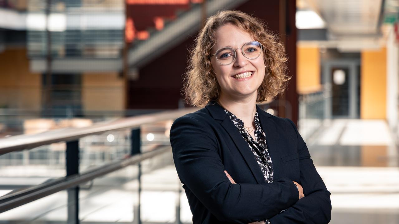 Alexandra Dahlberg standing in a corridor, smiling at the camera