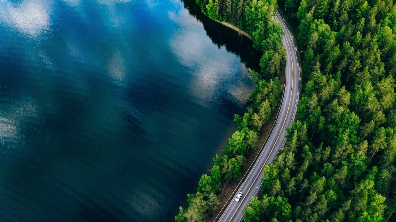 A view of a lake, a forest and a road in Finland from above.