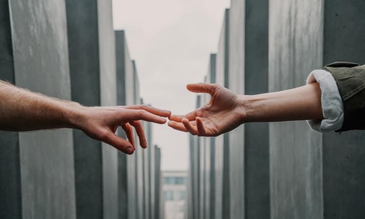 Two hands touching each other between buildings