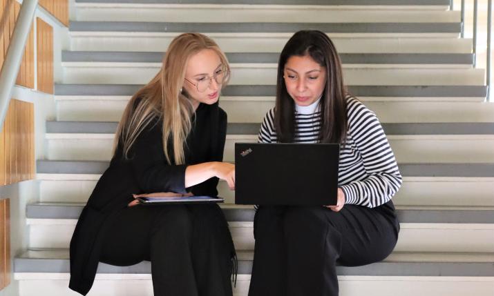 Two Hanken students sitting on the stairs looking at a laptop