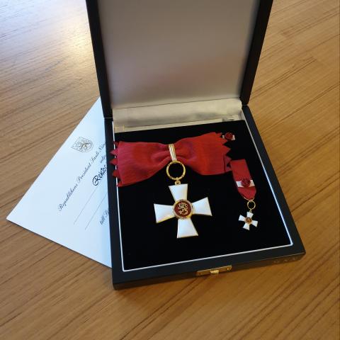 En bild på Karen Spens utmärkelsetecken Kommendörstecknet av Finlands Lejons orden i sin ask.