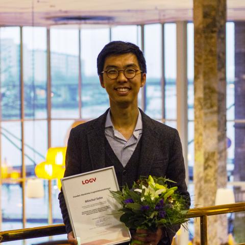 Minchul Sohn står med sitt pris och blommor i händerna.