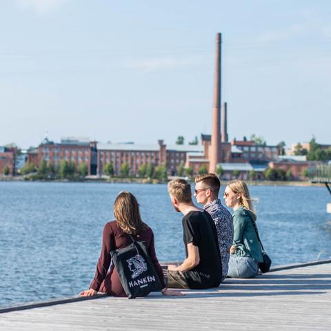En grupp personer sitter på en brygga i solskenet