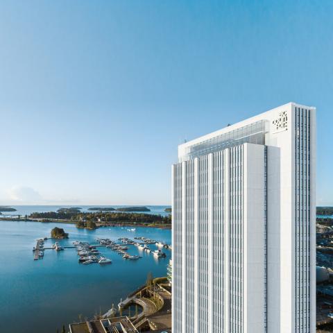 En hög kontorsbyggnad med havet i bakgrunden.