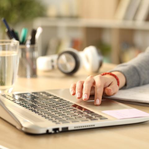 Bild av en dator och en människa som gör anteckningar med penna och papper