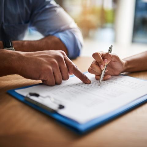 Personer som sitter vid ett bord och skriver under ett kontrakt