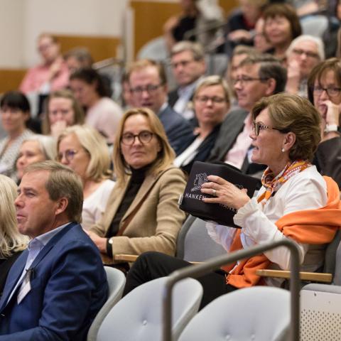 Människor som sitter i ett auditorium och en kvinna som ställer en fråga
