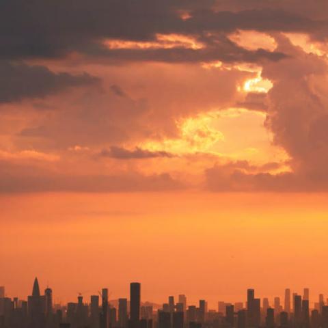 Stadslandskap i horisonten med solljus bakom molnen