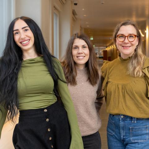 Researchers Leyla Yacine, Emma Nordbäck and Hertta Vuorenmaa stand beside each other in the Hanken corridor