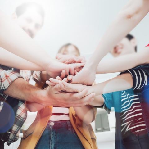 A group of people standing together with their hands stacked on top of each other
