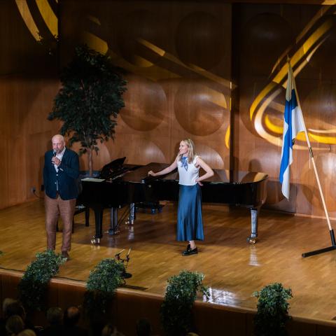 Two persons standing on the stage in Hanken's Assembly Hall